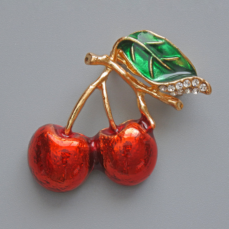 Brosche „Kirschen“ mit roter und grüner Emaille, weißen Strasssteinen, goldfarbenem Metall 22 × 35 mm